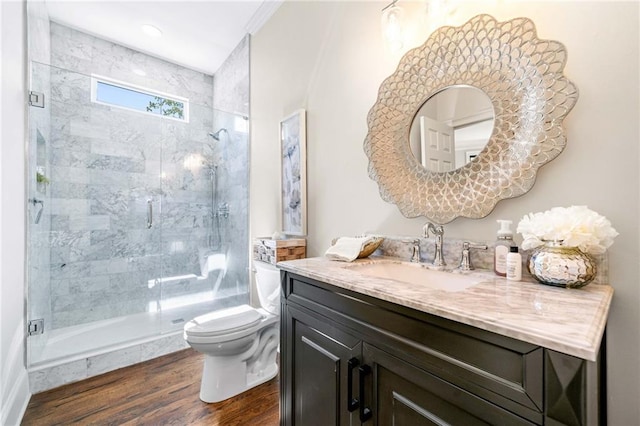 bathroom with toilet, a shower stall, wood finished floors, and vanity