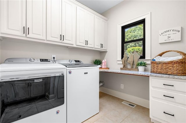 laundry area featuring washing machine and dryer, cabinet space, light tile patterned floors, and baseboards