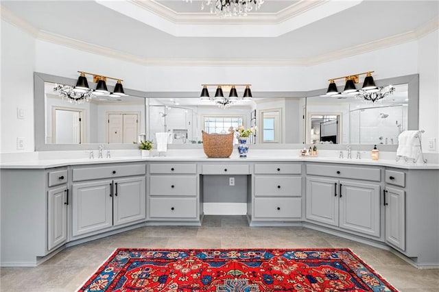 full bathroom featuring a chandelier, crown molding, a shower stall, a raised ceiling, and double vanity