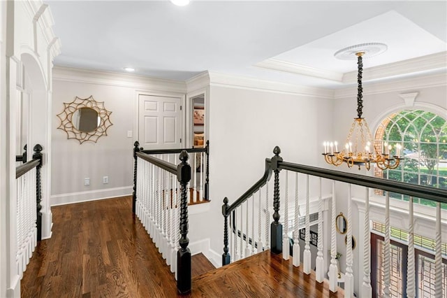 hall featuring a chandelier, an upstairs landing, wood finished floors, baseboards, and ornamental molding