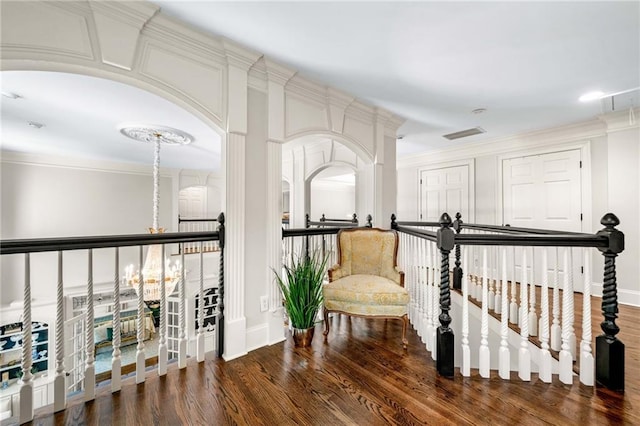 living area with baseboards, ornamental molding, wood finished floors, and a chandelier