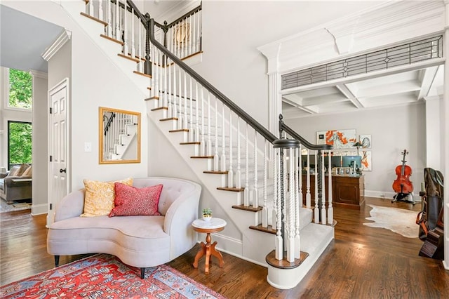 stairway with baseboards, wood finished floors, coffered ceiling, beamed ceiling, and crown molding