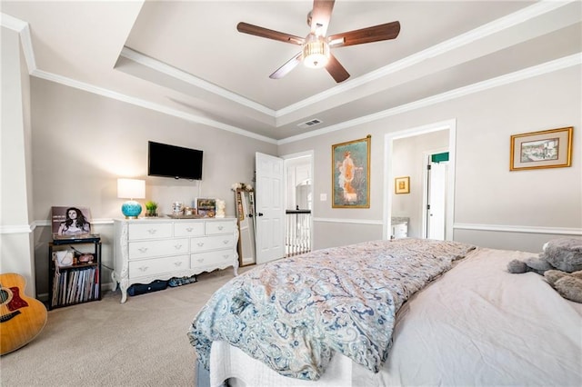 bedroom featuring light colored carpet, a tray ceiling, crown molding, and a ceiling fan