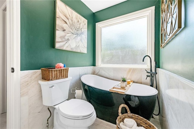 full bathroom with toilet, tile walls, a wainscoted wall, and a freestanding tub