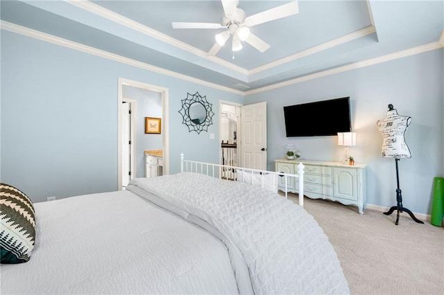 bedroom with light colored carpet, ornamental molding, a raised ceiling, baseboards, and ensuite bathroom