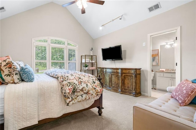 bedroom featuring light colored carpet, ensuite bathroom, track lighting, ceiling fan, and high vaulted ceiling