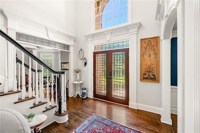 entryway with french doors, wood finished floors, arched walkways, a high ceiling, and stairs