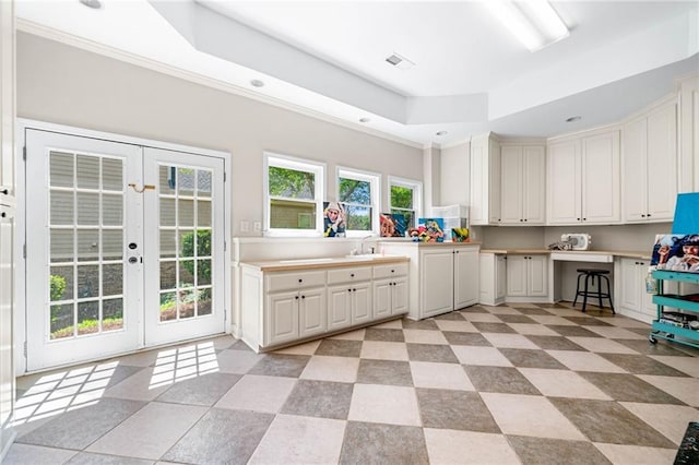 kitchen featuring a tray ceiling, french doors, light countertops, recessed lighting, and white cabinetry