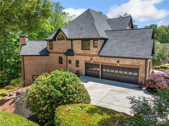 view of front of property featuring concrete driveway, roof with shingles, a chimney, and brick siding