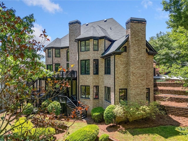 rear view of property featuring a chimney, stairs, and brick siding