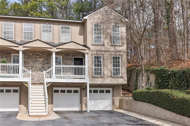 view of front of property with stone siding, a porch, aphalt driveway, and stucco siding