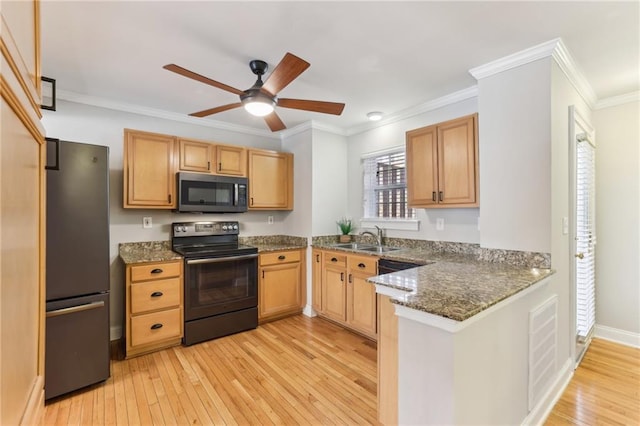 kitchen with visible vents, light wood-style floors, freestanding refrigerator, a sink, and black / electric stove