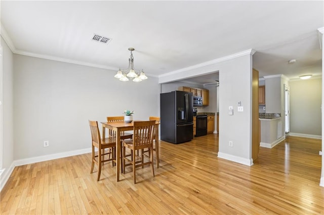 dining room featuring ornamental molding, visible vents, light wood finished floors, and an inviting chandelier