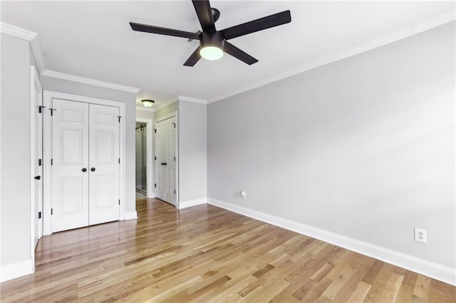 unfurnished bedroom with light wood-type flooring, multiple closets, baseboards, and crown molding