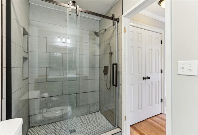 full bathroom with a shower stall, ornamental molding, and wood finished floors