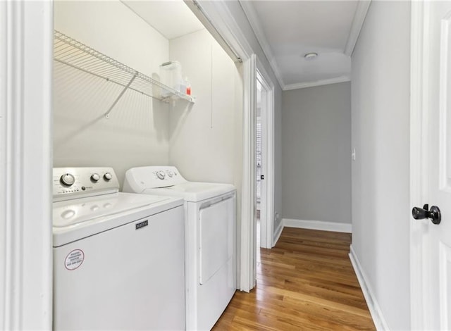 laundry room with washing machine and clothes dryer, light wood-style flooring, ornamental molding, laundry area, and baseboards