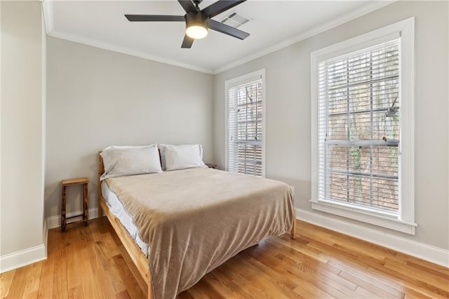 bedroom with baseboards, crown molding, and light wood finished floors