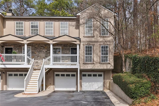 multi unit property with aphalt driveway, stairs, and stucco siding