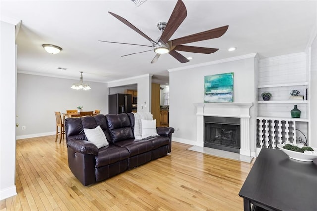 living room with ornamental molding, a fireplace, light wood-style floors, and baseboards