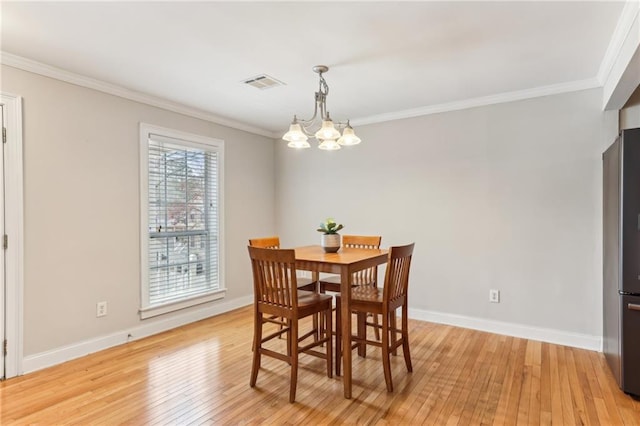 dining area with a chandelier, light wood-type flooring, visible vents, and crown molding