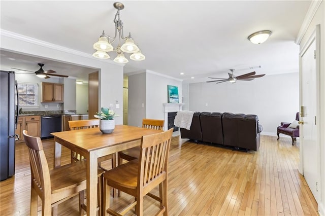 dining room with light wood-style floors, crown molding, a fireplace, and visible vents