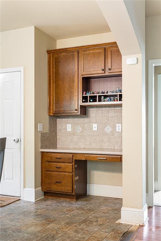 1110 Cureton Dr, Austell, GA 30106 - kitchen with tasteful backsplash, baseboards, light countertops, and brown cabinetry