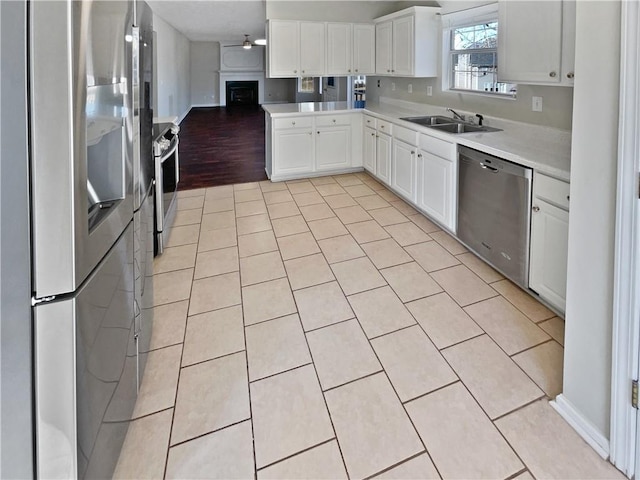 kitchen with sink, ceiling fan, light tile patterned floors, white cabinetry, and stainless steel appliances