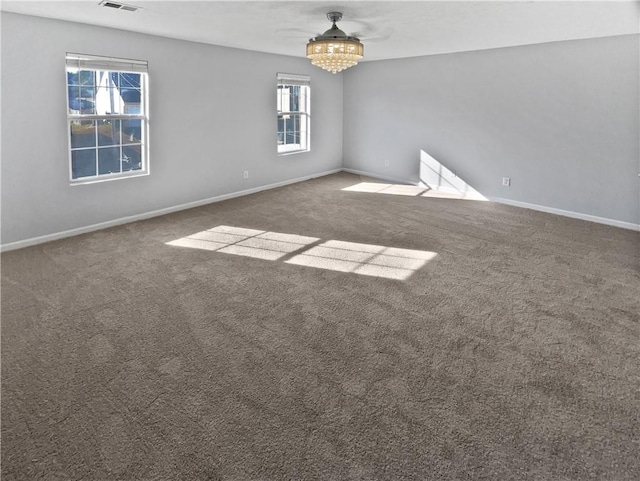 carpeted empty room with a notable chandelier