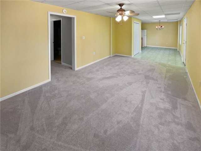 empty room featuring a drop ceiling, light colored carpet, and ceiling fan with notable chandelier