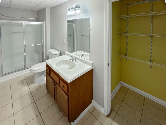 bathroom featuring tile patterned floors, toilet, vanity, and walk in shower