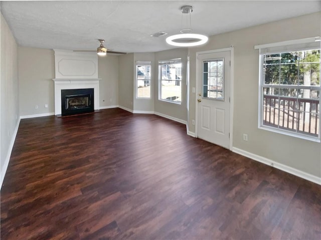 unfurnished living room with ceiling fan, a large fireplace, and dark wood-type flooring