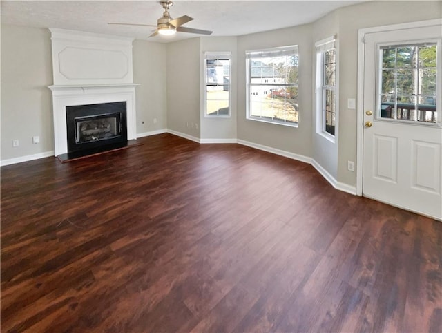 unfurnished living room featuring dark hardwood / wood-style flooring, a large fireplace, and ceiling fan