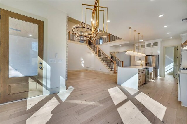 interior space with white cabinets, a chandelier, hanging light fixtures, a center island, and light wood-type flooring