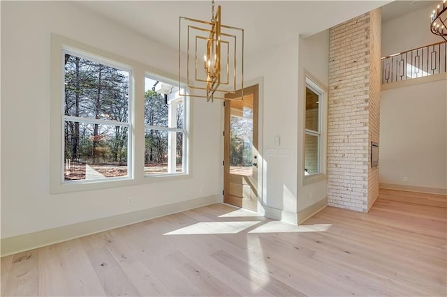 unfurnished dining area featuring light wood-type flooring and a notable chandelier