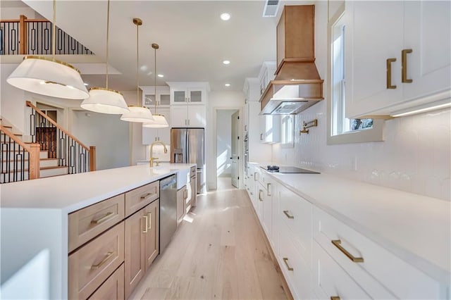 kitchen with custom exhaust hood, hanging light fixtures, stainless steel appliances, light hardwood / wood-style floors, and white cabinets