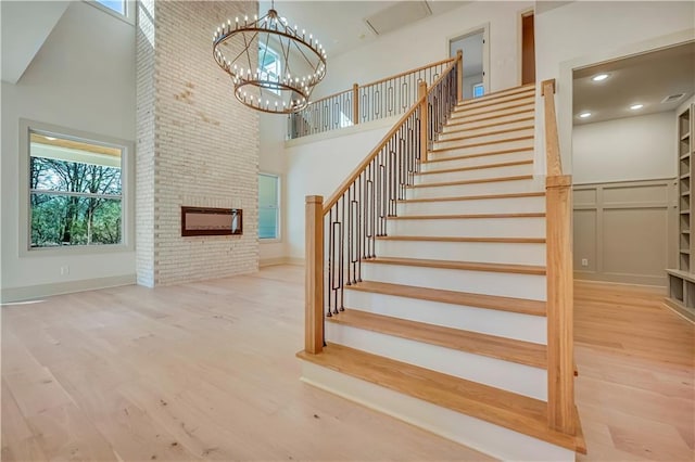 staircase with hardwood / wood-style flooring, a towering ceiling, and a notable chandelier