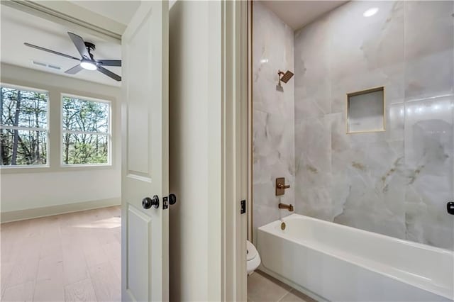 bathroom featuring tiled shower / bath combo, ceiling fan, and toilet