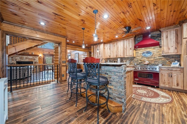 kitchen with wall chimney range hood, hanging light fixtures, high quality range, dark hardwood / wood-style floors, and light brown cabinetry