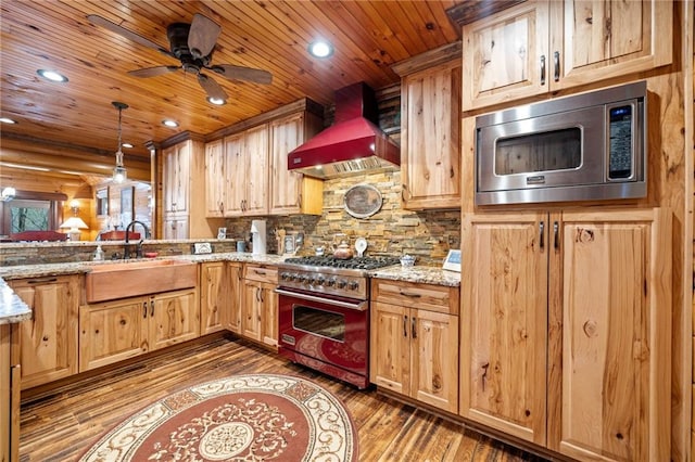 kitchen featuring premium range hood, sink, decorative light fixtures, stainless steel appliances, and light stone countertops