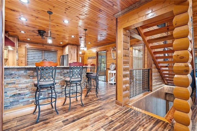 kitchen with wooden walls, wood-type flooring, stainless steel fridge, kitchen peninsula, and wooden ceiling