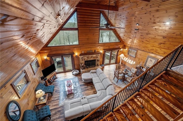 living room with ceiling fan, wooden walls, hardwood / wood-style floors, and high vaulted ceiling