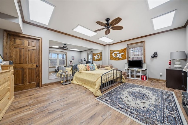 bedroom with a skylight, crown molding, light hardwood / wood-style flooring, and ceiling fan