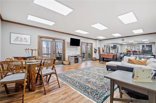 living room featuring crown molding, french doors, and light wood-type flooring