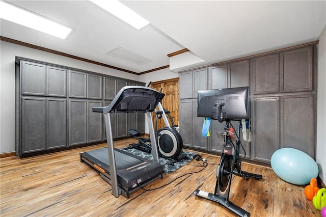 exercise room featuring crown molding and light wood-type flooring