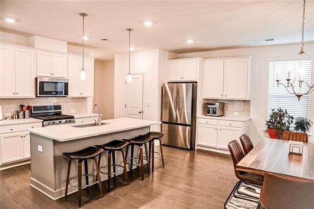 4734 Dewitt Dr, Duluth, GA 30097 - kitchen featuring stainless steel appliances, a sink, tasteful backsplash, a kitchen island with sink, and dark wood-type flooring