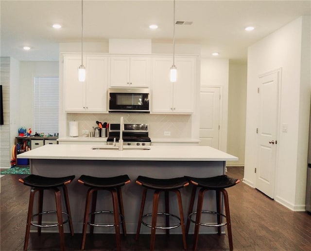 4734 Dewitt Dr, Duluth, GA 30097 - kitchen featuring appliances with stainless steel finishes, a sink, tasteful backsplash, an island with sink, and white cabinets