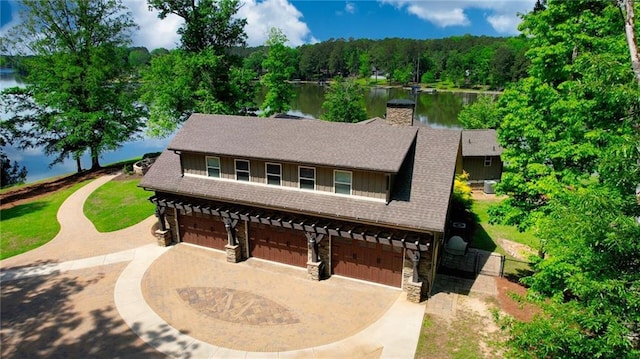 view of front facade with a water view, an attached garage, driveway, and stone siding