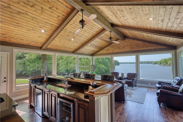 interior space with a water view, wine cooler, and beam ceiling