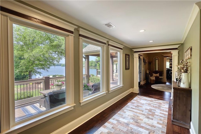 hallway featuring visible vents, ornamental molding, a water view, and a wealth of natural light