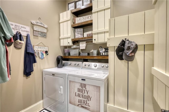washroom featuring cabinet space, separate washer and dryer, and baseboards